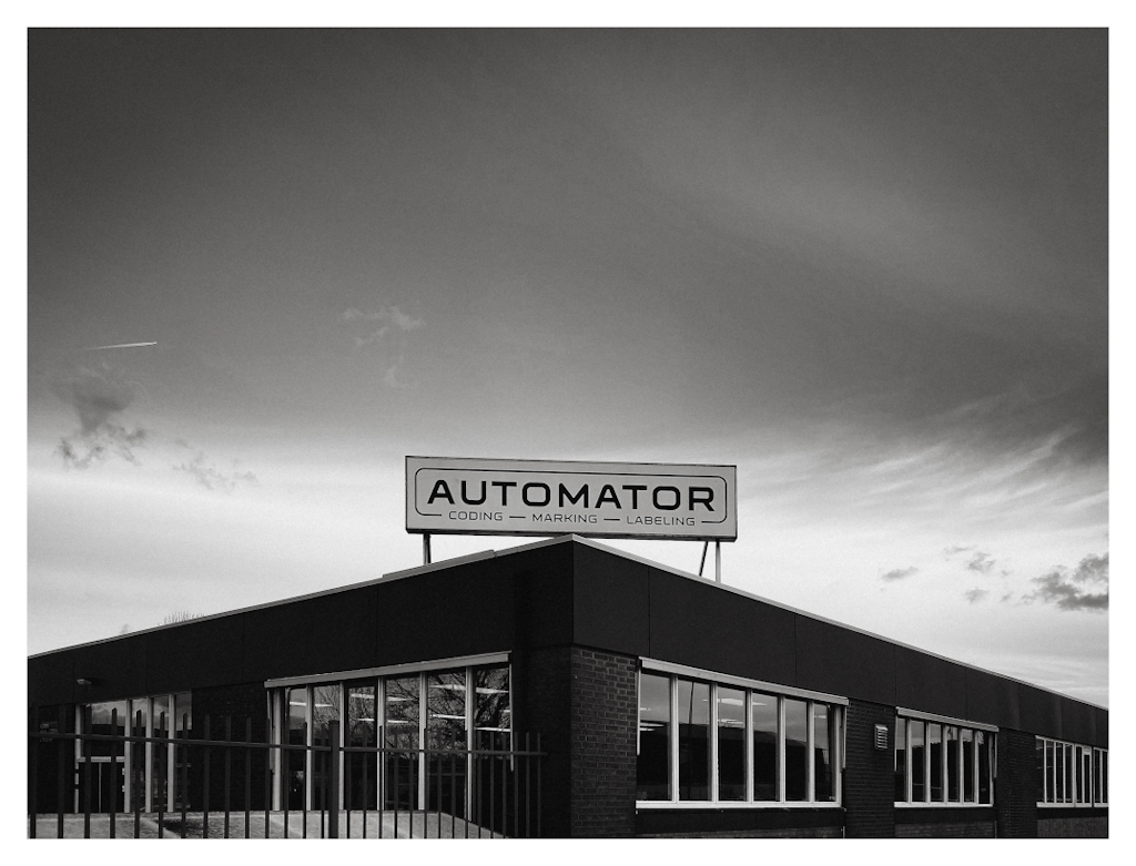 Sign saying Automator on top of a 1-story building, shown in B&W. 