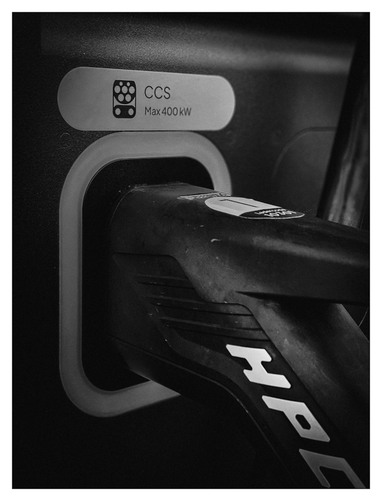 Detail of an EV charging cable connected to a charger, in black and white. 