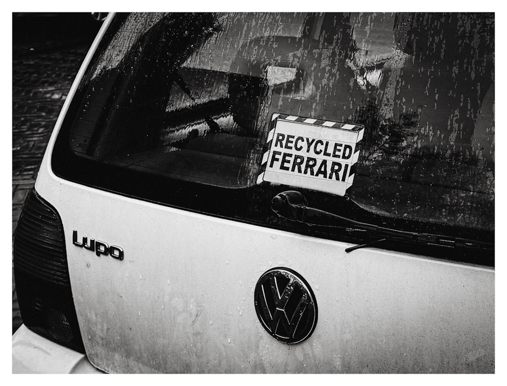 “Recycled Ferrari” sign on the back of a Volkswagen Lupo car 